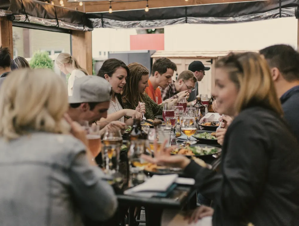 Friends sharing a long dinner table on a warm evening terrace